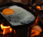 Gusseisernes Kochgerät am und im Feuer